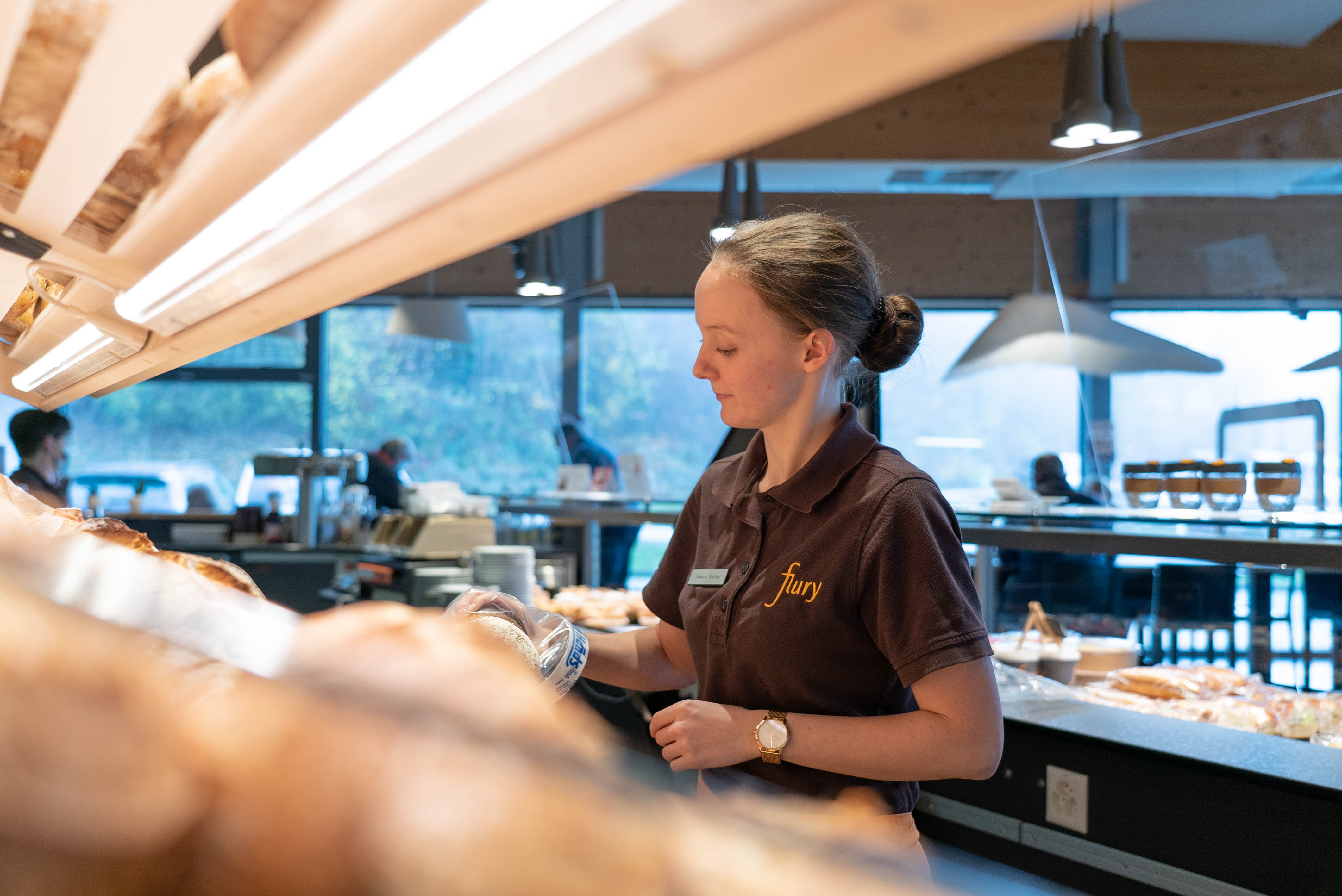 Verkäuferin hält ein Brot in der Hand.