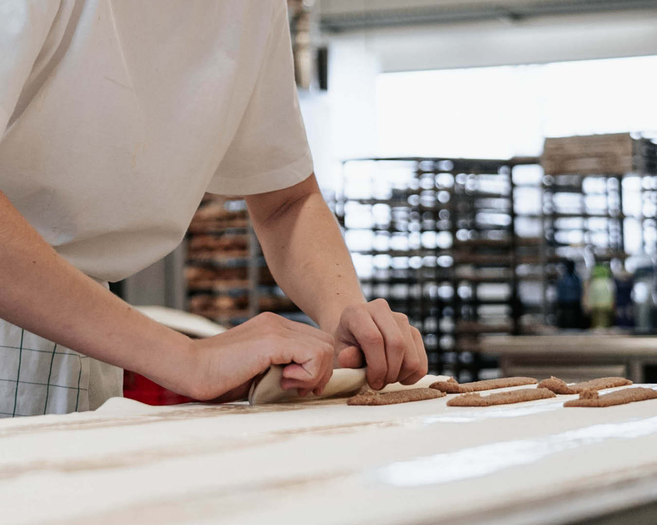 Innovation Bäckerin faltet mit den Händen Teig über Nussmasse
