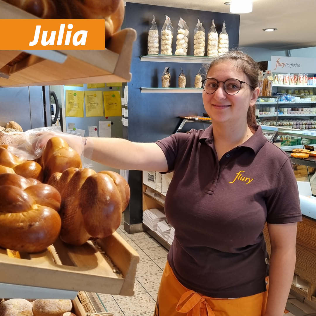 Unsere Lernende Julia räumt frische Butterzöpfe ins Brotgestell.