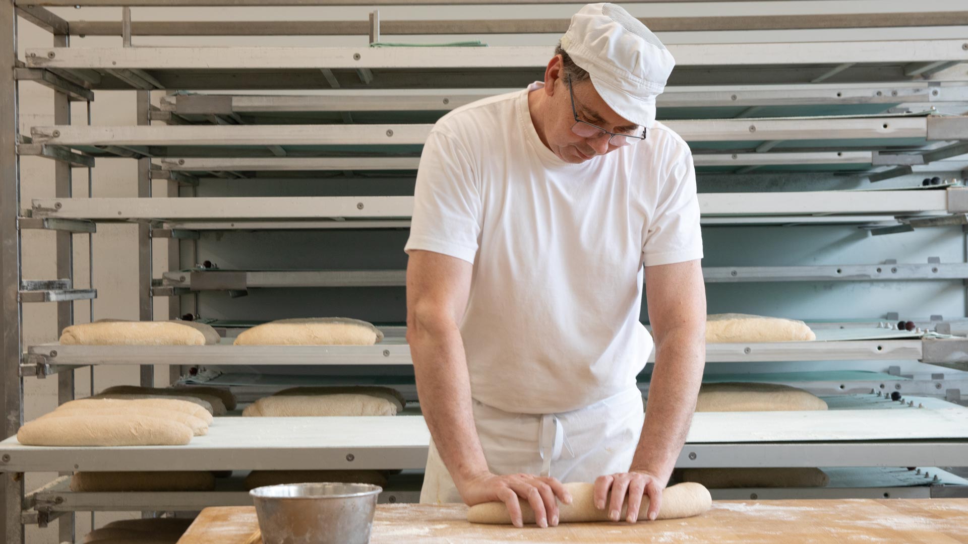 Bäcker arbeitet Teig auf und formt ihn zu Brot.