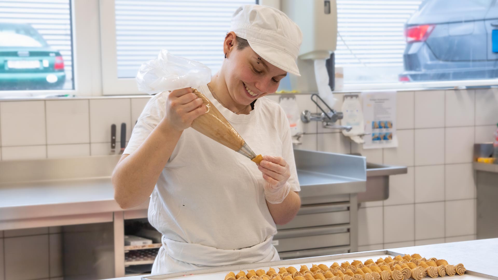 Konditorin dressiert Wienerkonfekt mit einer Buttercrème.