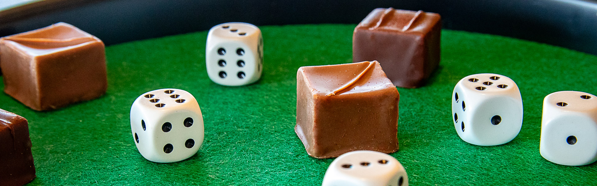 Header_Rabatt-Würfeln.jpg Truffe Würfel und Spielwürfel liegen auf einem Würfelbrett verteilt.