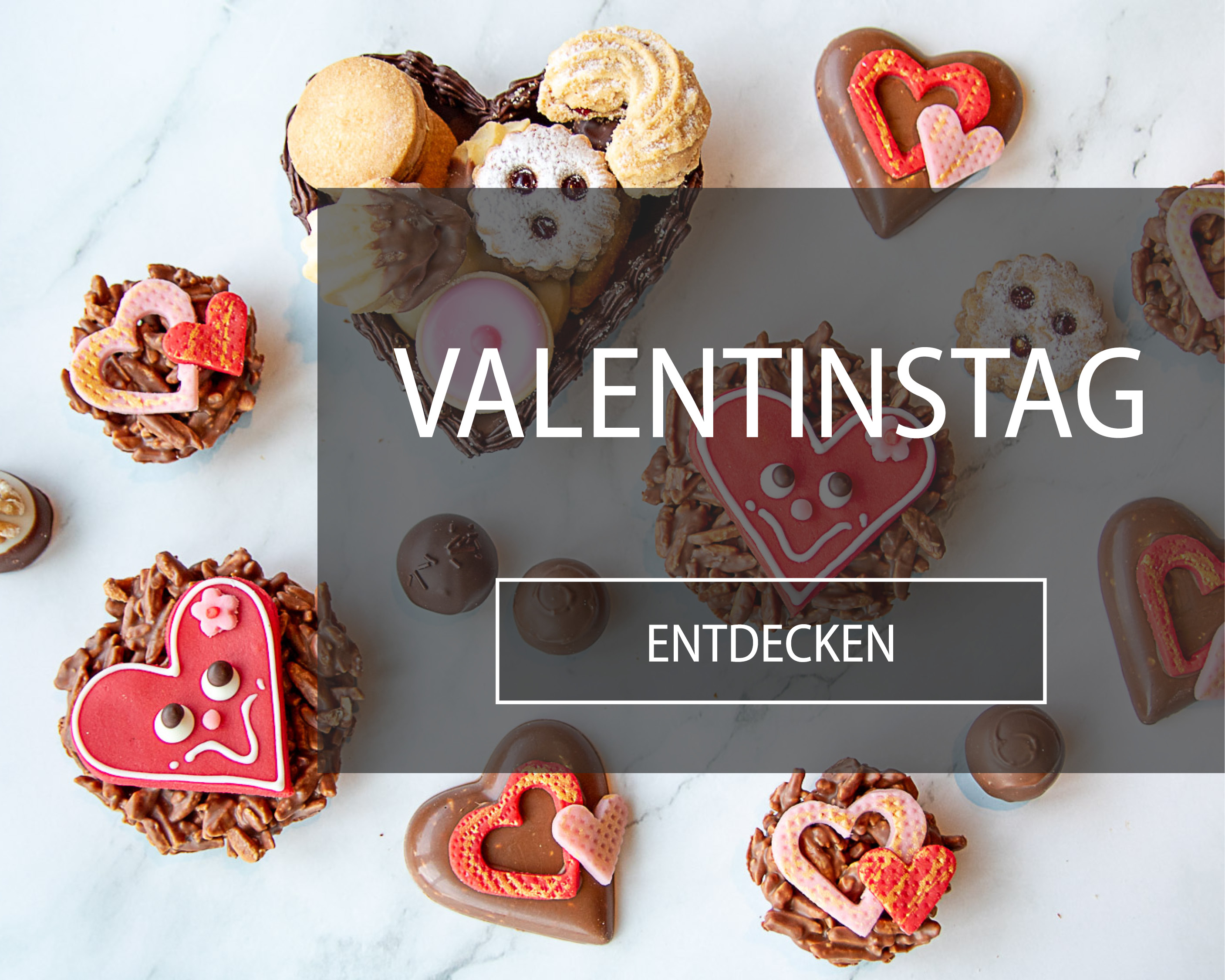 Valentinstagsspezialitäten aus Schokolade und Wienerkonfekt mit roten Marzipanherzen auf Marmortisch.
