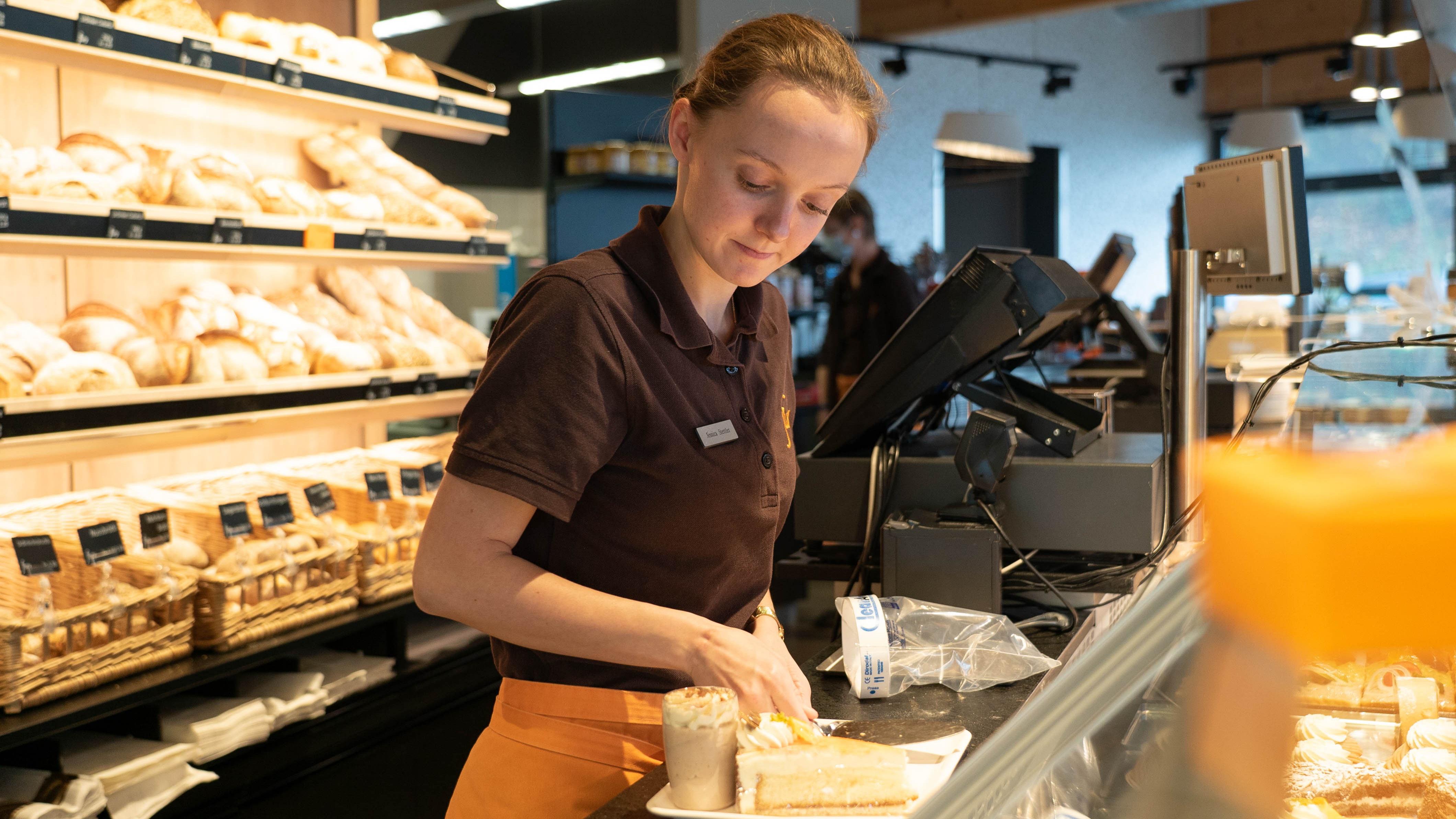 Lernende Verkauf richtet Patisserie an, um diese dem Kunden mitzugeben.