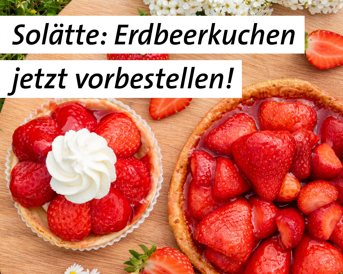 Erdbeertörtli und Erdbeerchüechli auf einem Holzbrett mit Blumen und Erdbeeren.