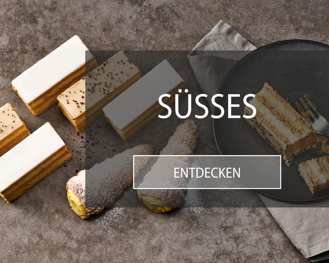 Cremeschnitten in verschiedenen Sorten sowie Vanille Cornet auf einem Tisch angerichtet.