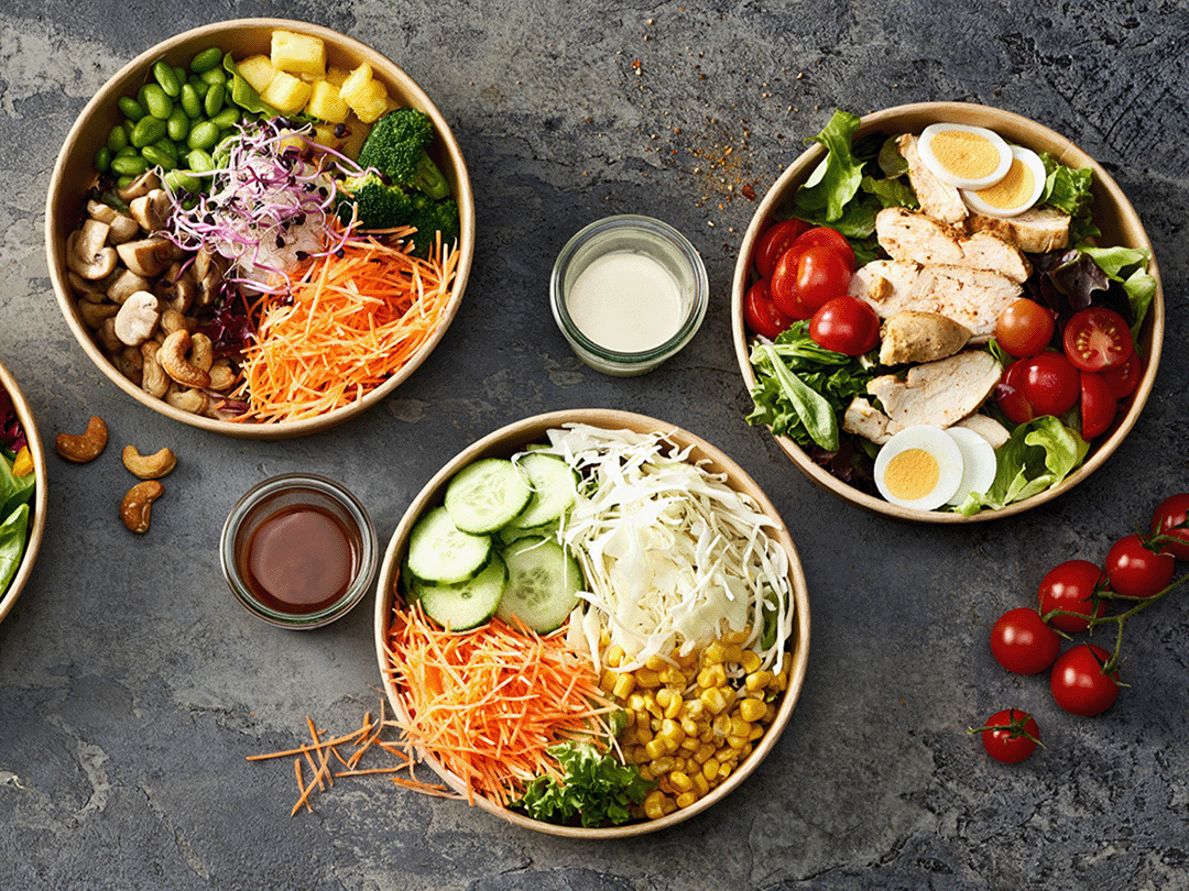 Verschiedene Salate in Kartonsch&uuml;sseln mit frischen Zutaten und verschiedenen Dressings.