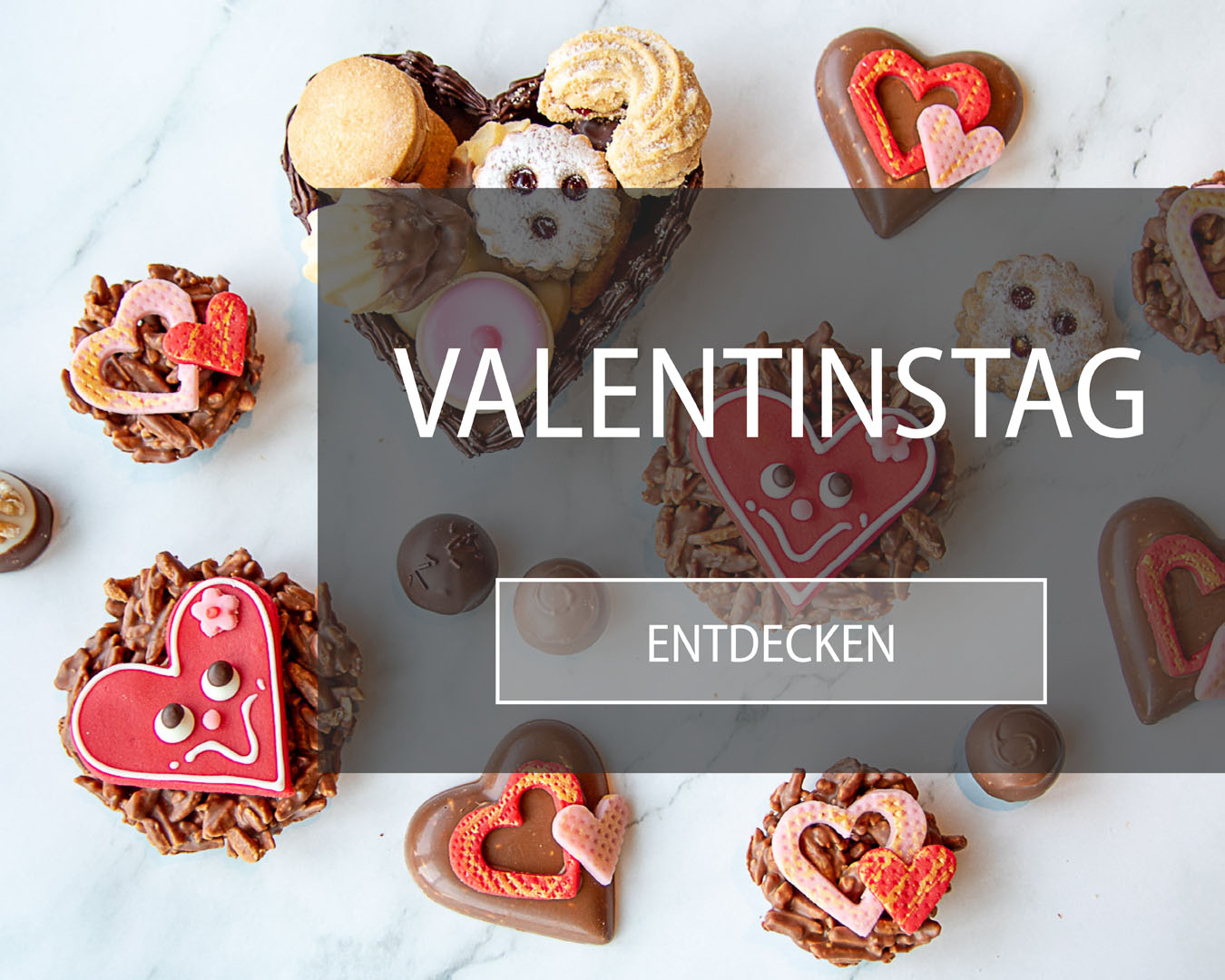 Valentinstagsspezialitäten aus Schokolade und Wienerkonfekt mit roten Marzipanherzen auf Marmortisch.
