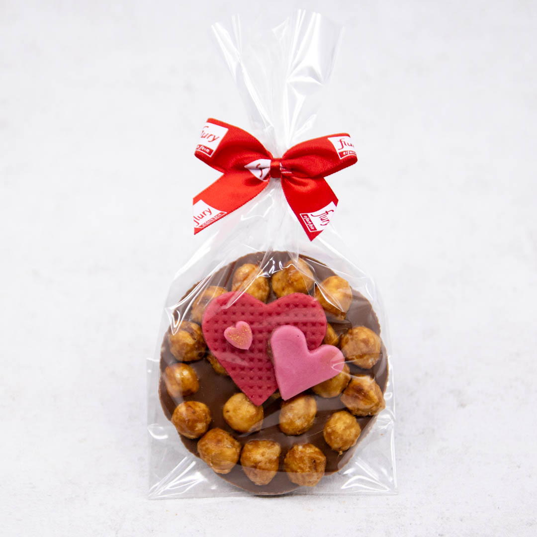 Nussknacker Herz verpackt mit Masche, caramelisierte, ganze Haselnüsse in Schokolade, mit Marzipanherz-Decor.