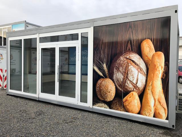 Provisorischer Verkaufscontainer für Subingen mit grosser Fensterfront und Brotbildern.
