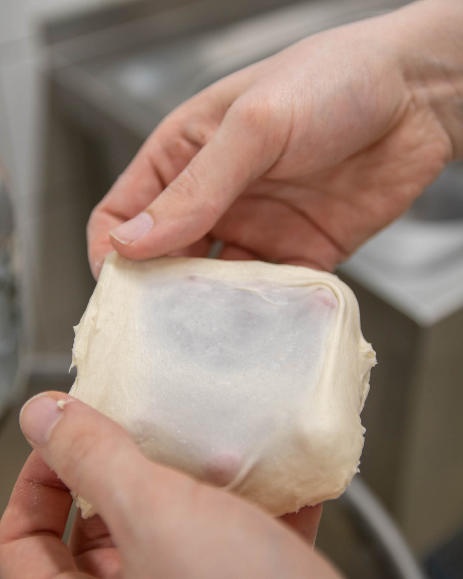 Nicola prüft, ob der WEggliteig gut ist, indem er ihn auseinanderzieht.