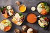 Verschiedene Salate in Kartonschüsseln mit frischen Zutaten und verschiedenen Dressings.