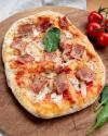 Pinsa Prosciutto auf einem Holzbrett